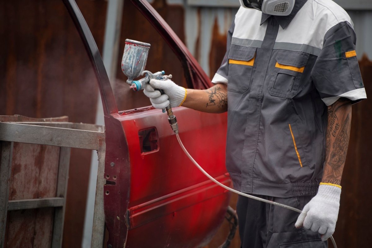 trabajador pintando coche de rojo